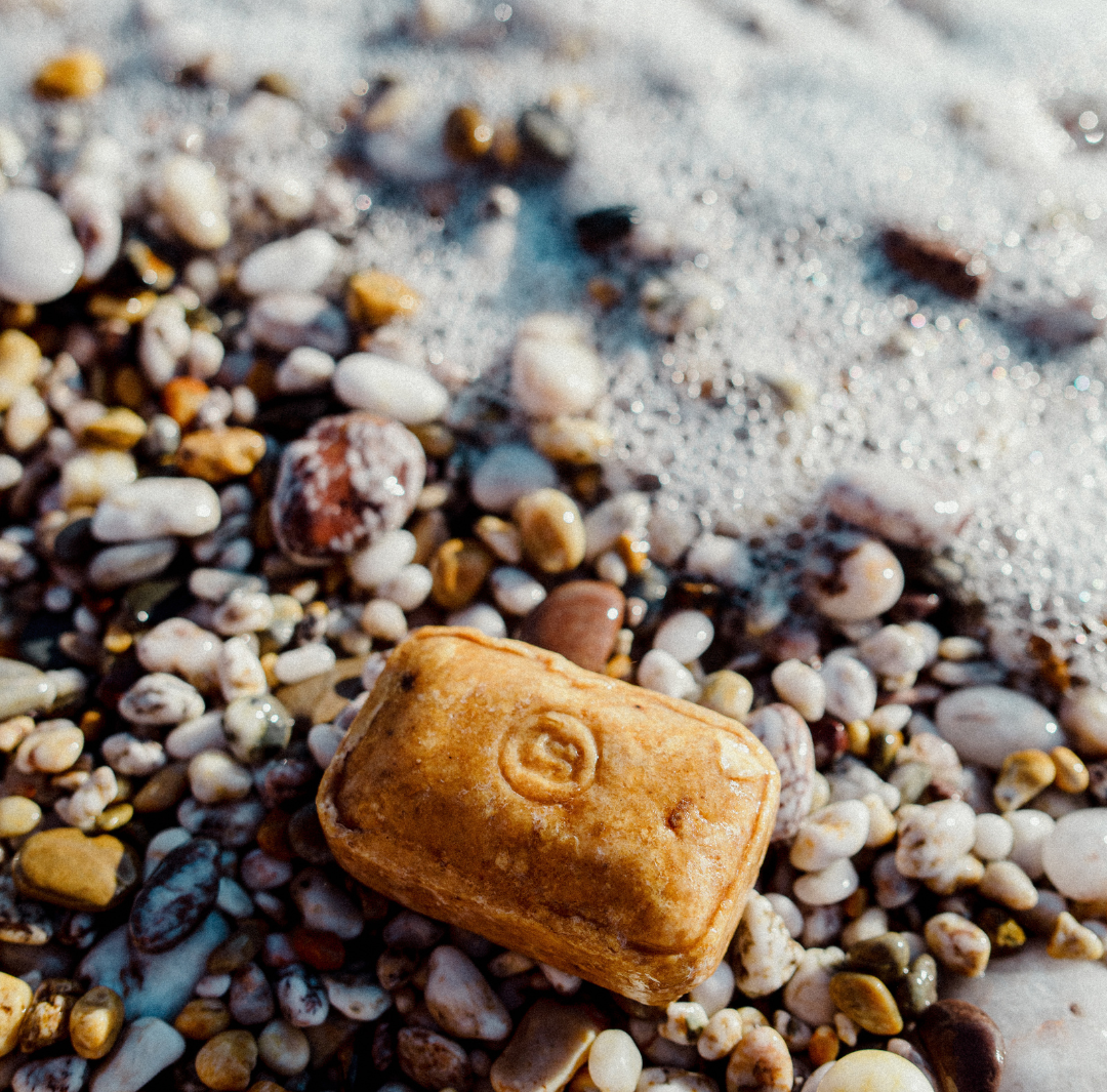 African Shea Black Soap on a pebbled beach image 1