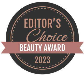 A circular black and pink logo for the "Editor's Choice Beauty Award 2023." The logo has a dotted outline, and the words "EDITOR'S Choice" are written in a mix of large and smaller fonts. A pink ribbon banner crosses the center with the words "BEAUTY AWARD," and "2023" is at the bottom which Aviela Skincare won