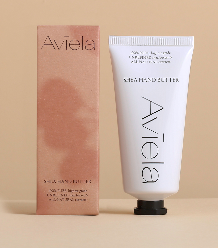 A product shot of Aviela Shea Hand Butter. The rectangular, peach-colored box stands next to a white tube of the hand butter with a black cap. Both the box and the tube have the product name and a description of the ingredients, which include "100% PURE, highest grade UNREFINED shea butter & ALL-NATURAL extracts."