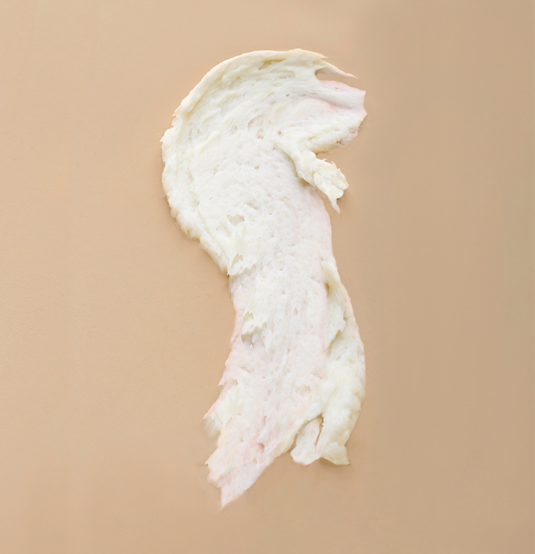 A vertical, abstract smear of a thick, creamy, off-white Pure Shea Butter, 100% Natural, is on a light tan background. The texture is visible with some darker, pinkish tones near the bottom.