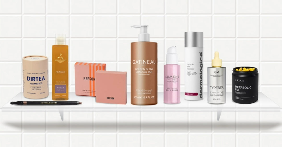 A collection of various beauty and wellness products displayed on two white shelves against a white tiled background.